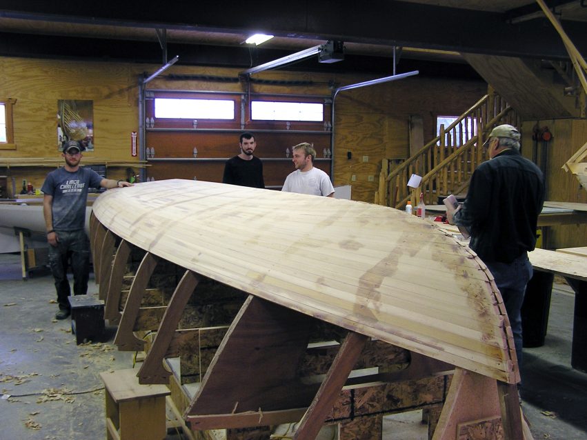 The cedar on and getting sanded fair before getting coated with epoxy and glassed by second-year Great Lakes Boatbuilding School students: (l-r) Troy Huesdash, Matt Edmondson, Kris Kindt, and Del Jacobs.