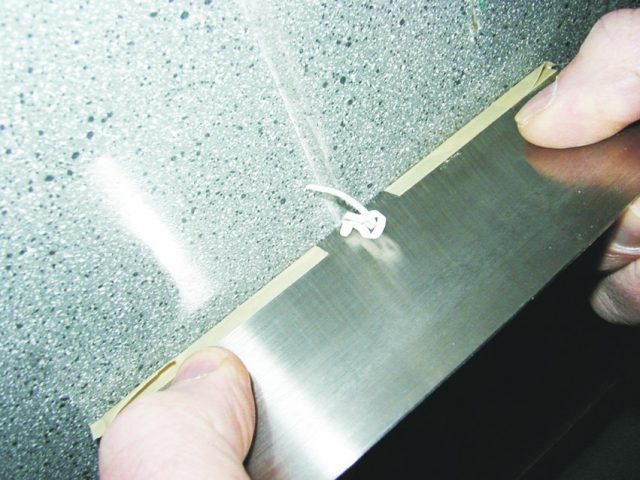 Tape can be used to isolate a small section of the scraper's edge to remove drips or clean up seams without affecting the surrounding area.