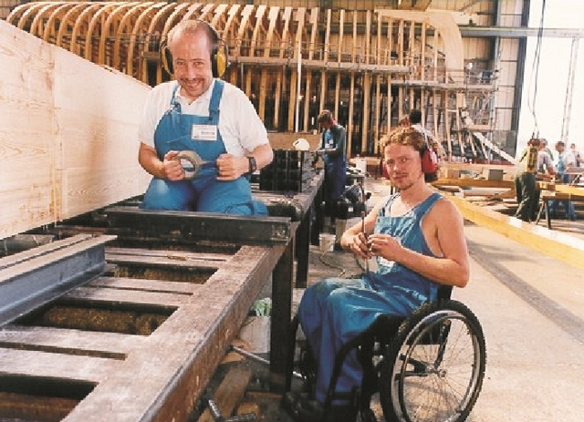 Two of the many volunteers at work on one of the custom laminating tables used to build frames and timbers.