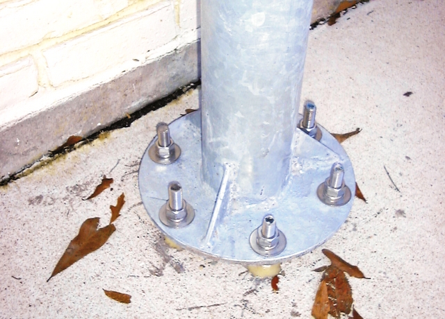 The base of the basketball goal post shows the six 5/8" threaded rods epoxied into the concrete driveway.