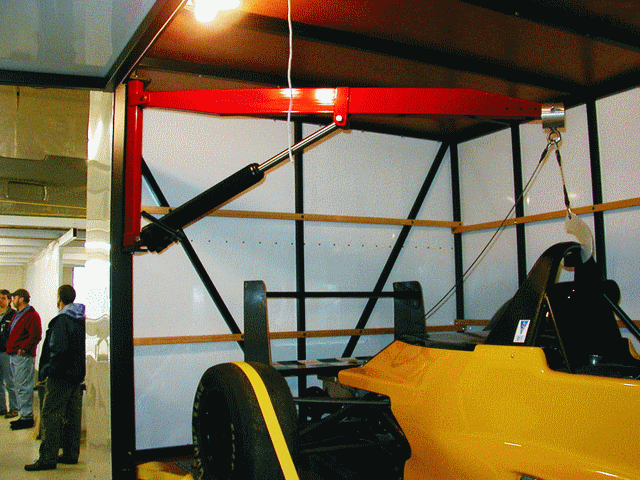 A come-along attached to a swinging arm loads and unloads the car. A cable lifts the car at its center of gravity, and it is swung onto the trailer.