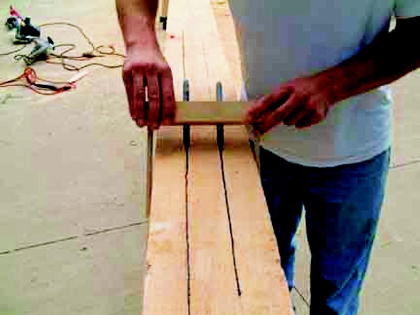 A spar-making jig is used to layout the flats of an octagon on a square, tapered spar. The lines are guides for planning the corners.