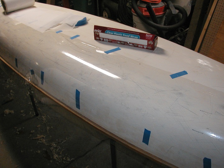 Plastic food wrap stretched over the bottom of the Gougeon 12.3 kayak hull to create a non-stick mold surface from which four fiberglass deck parts were made.