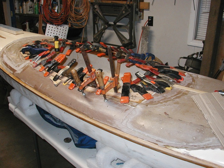 The four deck panels are installed and the 4mm plywood, under-edge coaming support is glued in place. The deck of the Gougeon 12.3 kayak was then faired and painted.