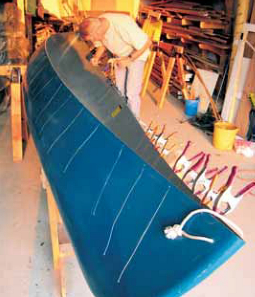 Stan Bradshaw taping cracks on the outside of the Royalex canoe with clear tape, readying cracks for G/flex injection.
