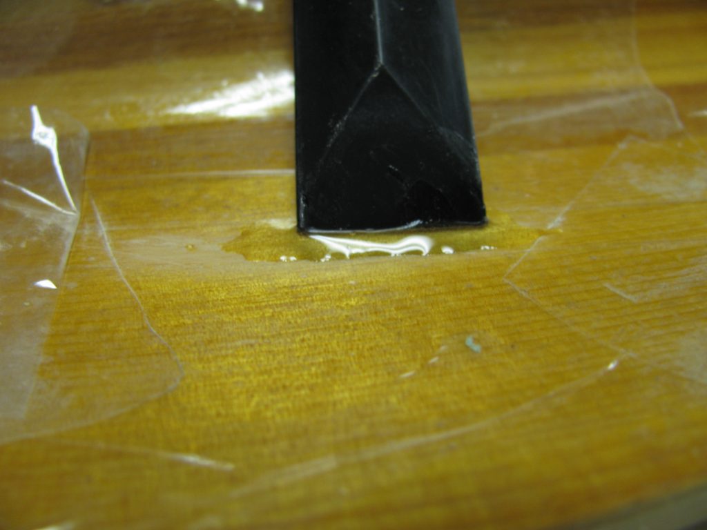 Abrade the dented varnish with an abrasive pad to dull the shine.