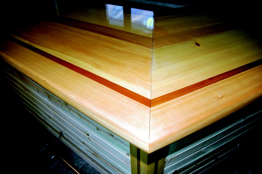 The corner detail showing the sitka spruce field with mahogany accent strips. The top has four coats of 105/207 wet sanded between the third and fourth coat.