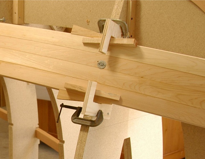 The ‘C’ shaped plywood jig has two screws that protrude slightly through the plywood.