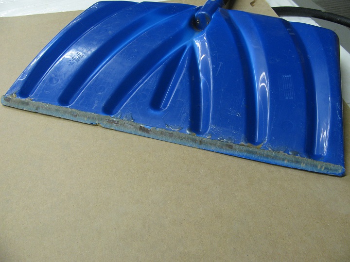 The working edge of my trusty blue snow shovel with the wear strips worn through.