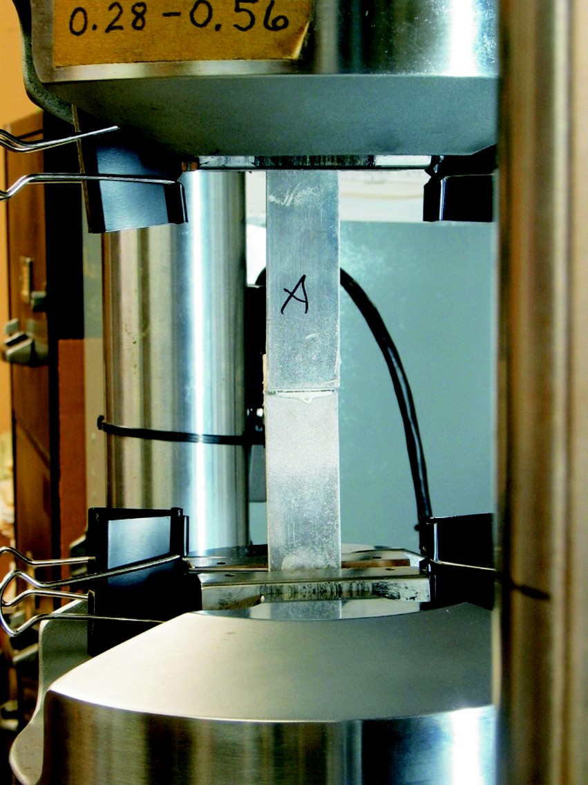 Single lap shear sample in the test machine. The sample is two aluminum plates glued with a 1/2" overlap.