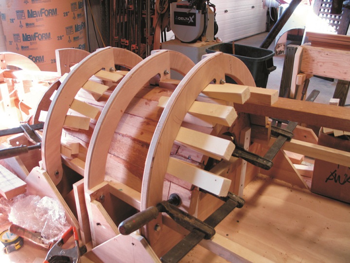 The staves of a horizontal reveal being glued in place using the plywood brackets to wedge the staves tight until the epoxy cured.