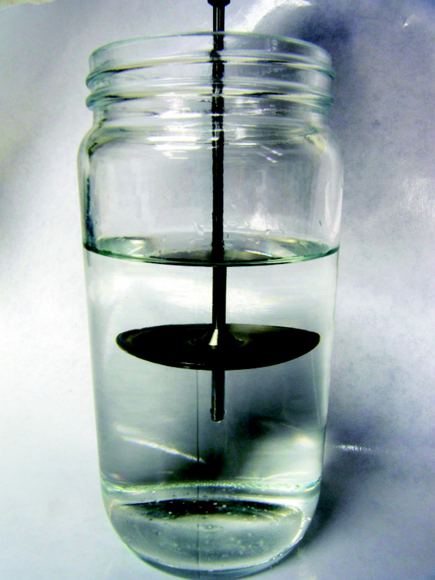 The rotational viscometer spindle suspended in a jar of epoxy resin.