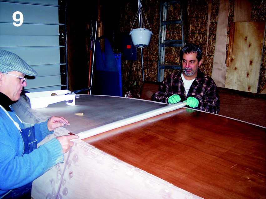 Captain James R. Watson and I applied the glass cloth by rolling it up halfway, coating the wood, then we both unrolled it over the wet-out epoxy surface.