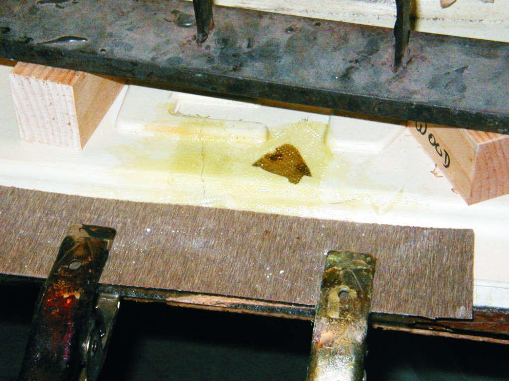 The grill is held against plastic covered plywood with clamps and weights so repairs will be flat and smooth.