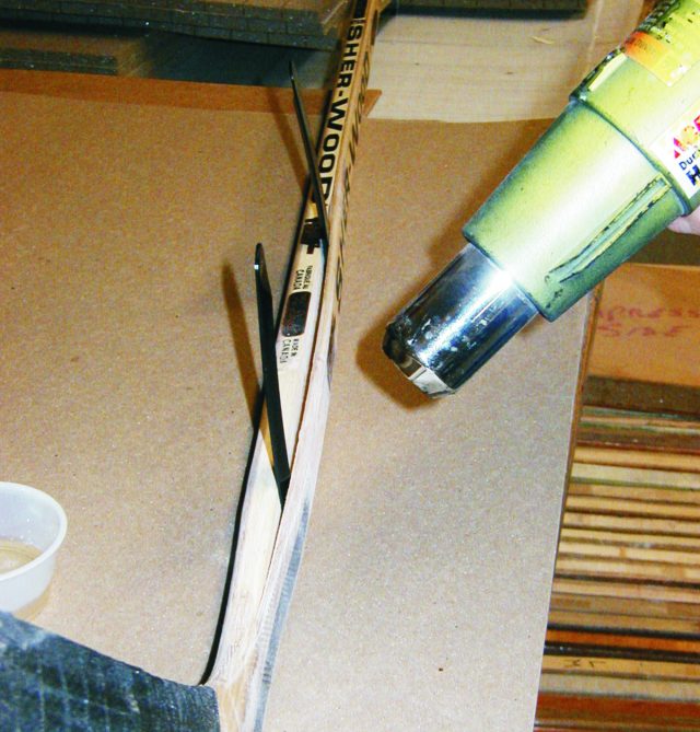 1. To repair the hockey stick, begin by opening the split, clean out any loose material, and warm the area with a heat gun.