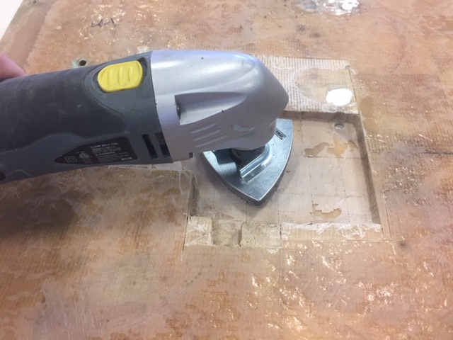 Sanding the sea hood's repair area with an oscillating saw.