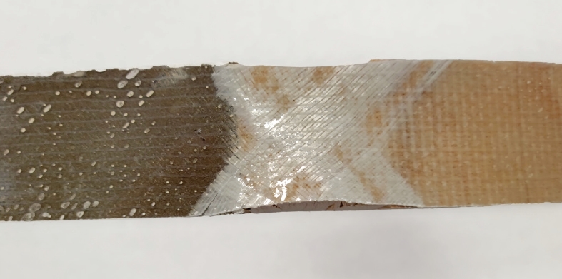 The fiberglass fractured at the transition from epoxy to balsa core in the epoxy-filled repair.